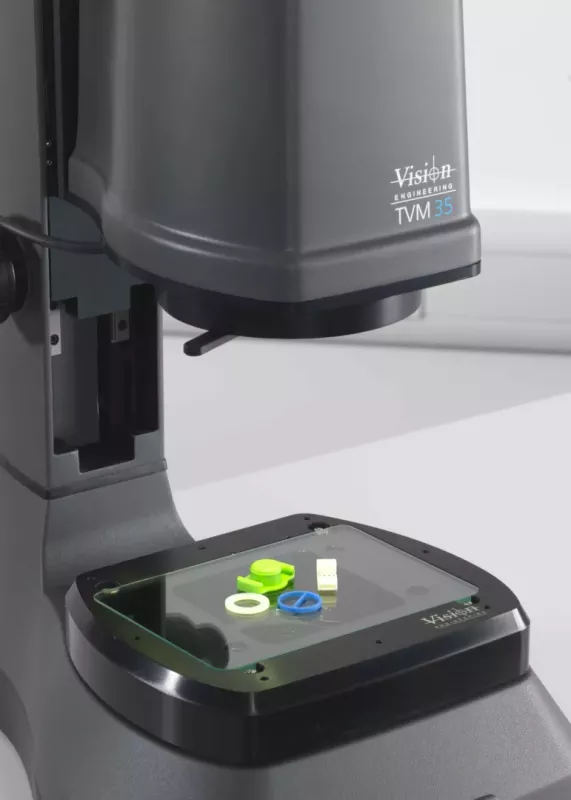 Małe elementy plastikowe ułożone na stole pomiarowym mikroskopu TVM35 podczas kontroli jakości