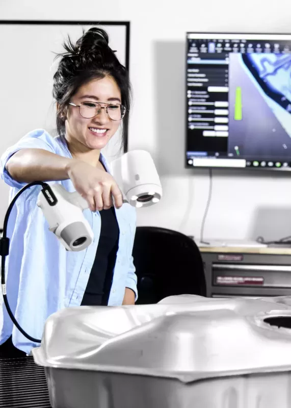 Student skanuje metalowy element skanerem Creaform, obserwując model 3D na ekranie