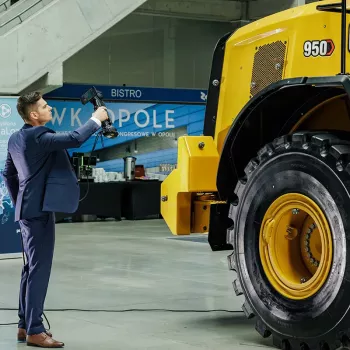 Operator skanerem 3D HandySCAN 3D MAX skanuje żółtą ładowarkę kołową CAT 950 – szybki pomiar dużych elementów na hali