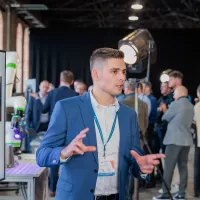 Ekspert tłumaczy wyniki skanowania 3D na ekranie; w&nbsp;tle cobot i&nbsp;uczestnicy wydarzenia.