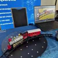 Model pociągu na obrotnicy obok laptopa – demonstracja procesu skanowania 3D.