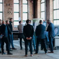 Grupa słuchaczy ogląda wyniki tomografii przemysłowej na monitorach podczas wydarzenia.