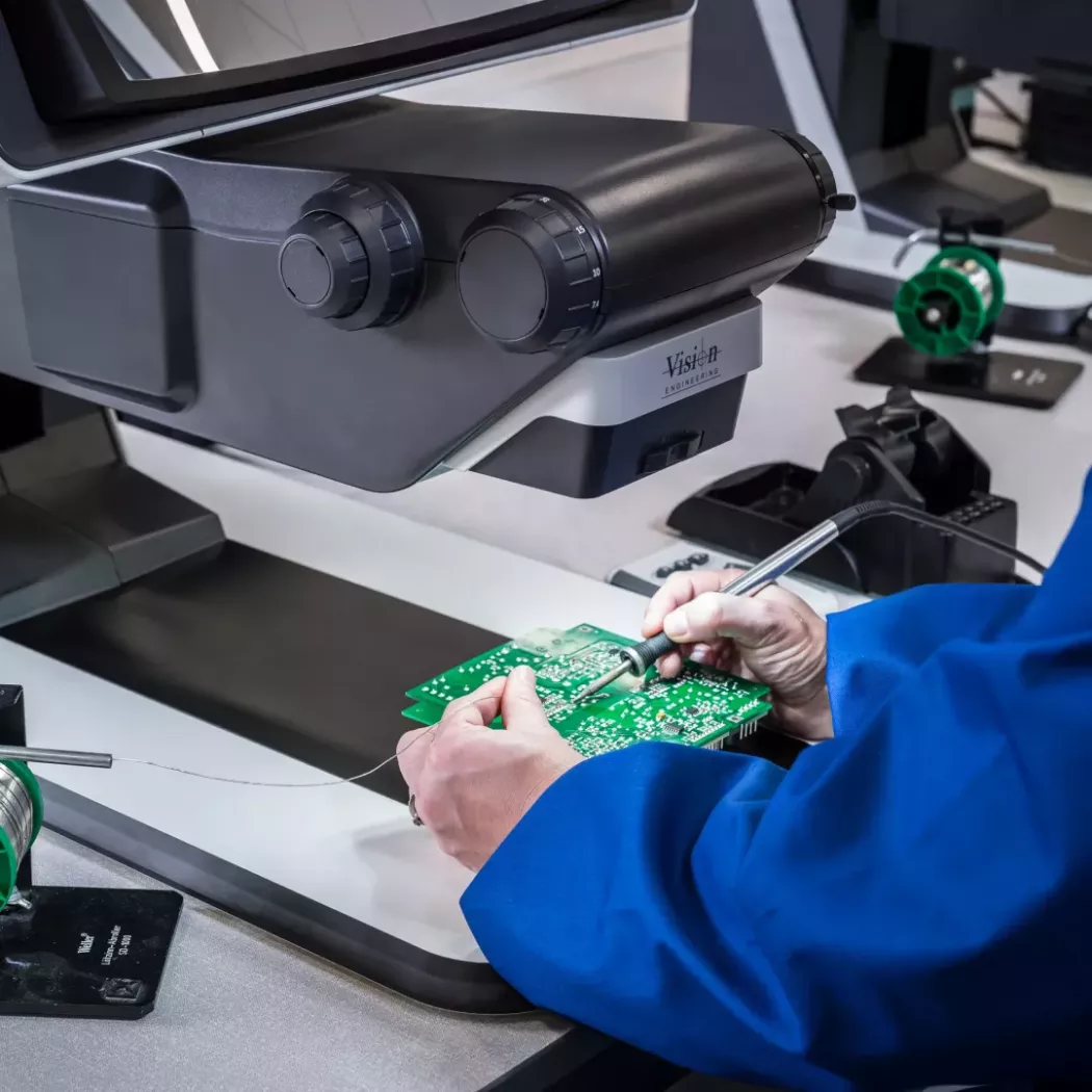 Operator lutujący płytkę PCB pod mikroskopem 3D FHD DRV-Z1 podczas precyzyjnej inspekcji elektroniki