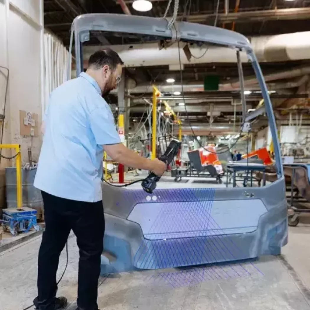 Skaner 3D Creaform HandySCAN 3D MAX wykonuje skan frontu autobusu na hali produkcyjnej — szybkie odwzorowanie geometrii