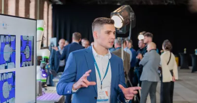 Ekspert tłumaczy wyniki skanowania 3D na ekranie; w&nbsp;tle cobot i&nbsp;uczestnicy wydarzenia.