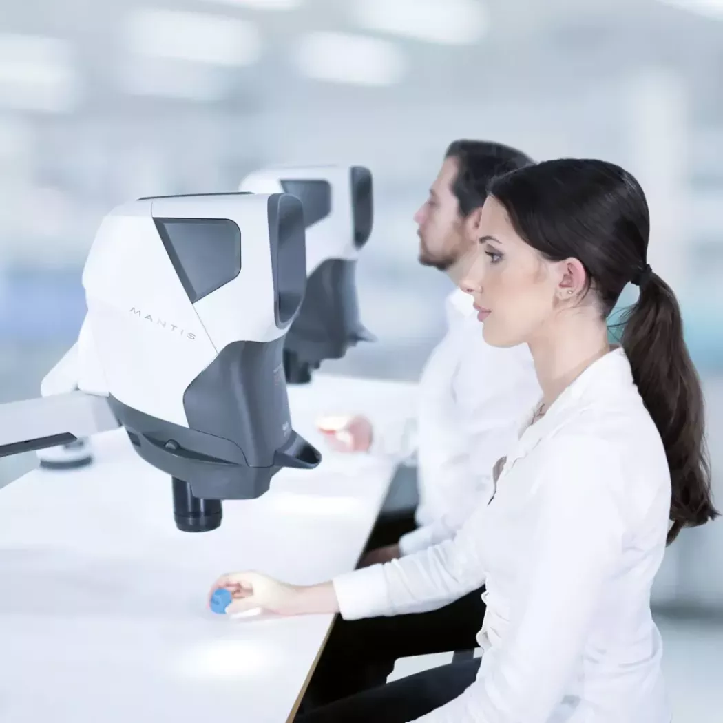 Dwóch operatorów korzysta z&nbsp;mikroskopu stereoskopowego Mantis PIXO na stanowisku