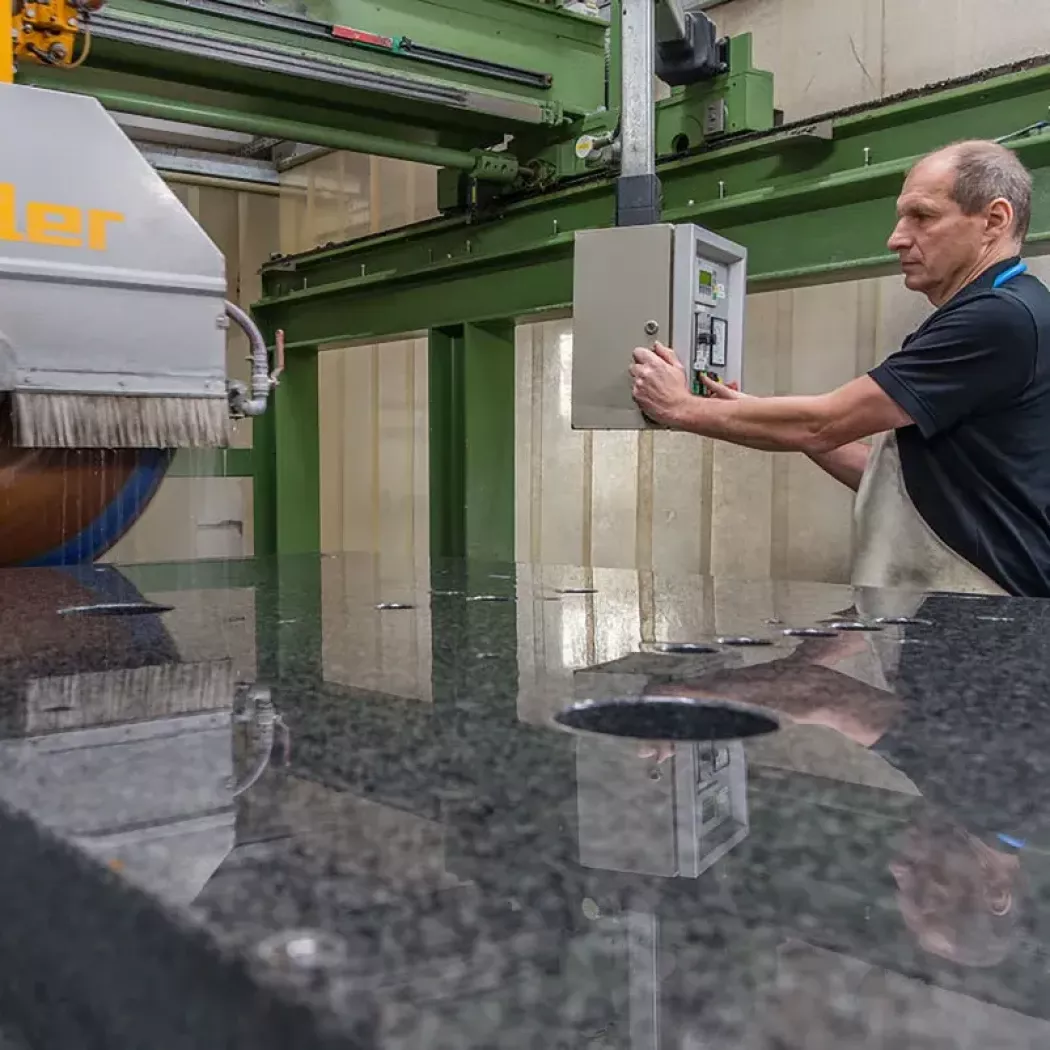 Operator obsługuje piłę L&ouml;ffler podczas obróbki na mokro płyty granitowej