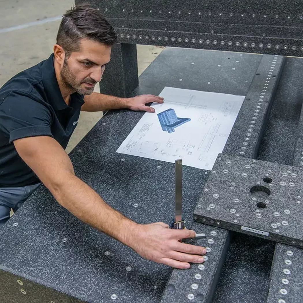Technik dopasowuje i mierzy elementy w specjalnej płycie granitowej zgodnie z dokumentacją