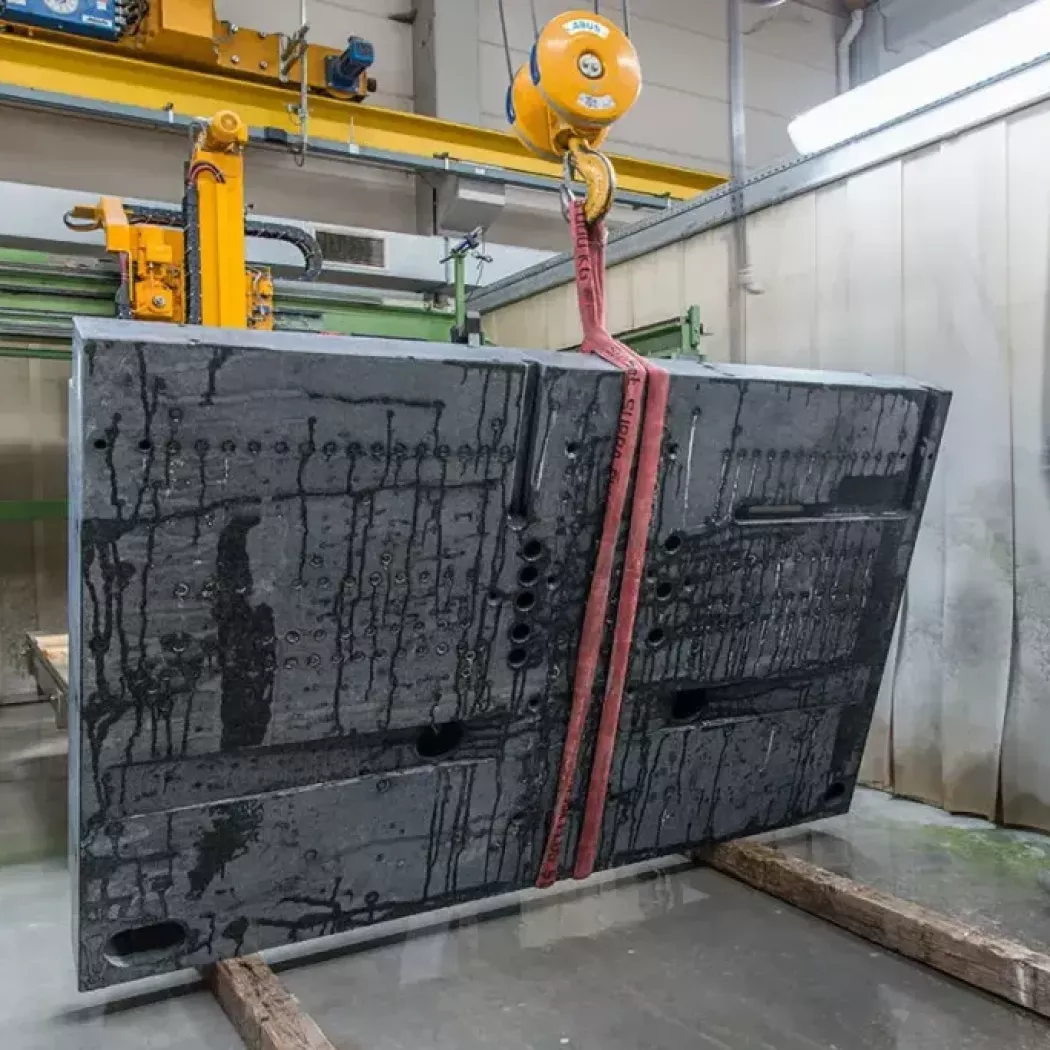 Duża płyta pomiarowa z otworami mocującymi podnoszona pasem przez suwnicę — Planolith