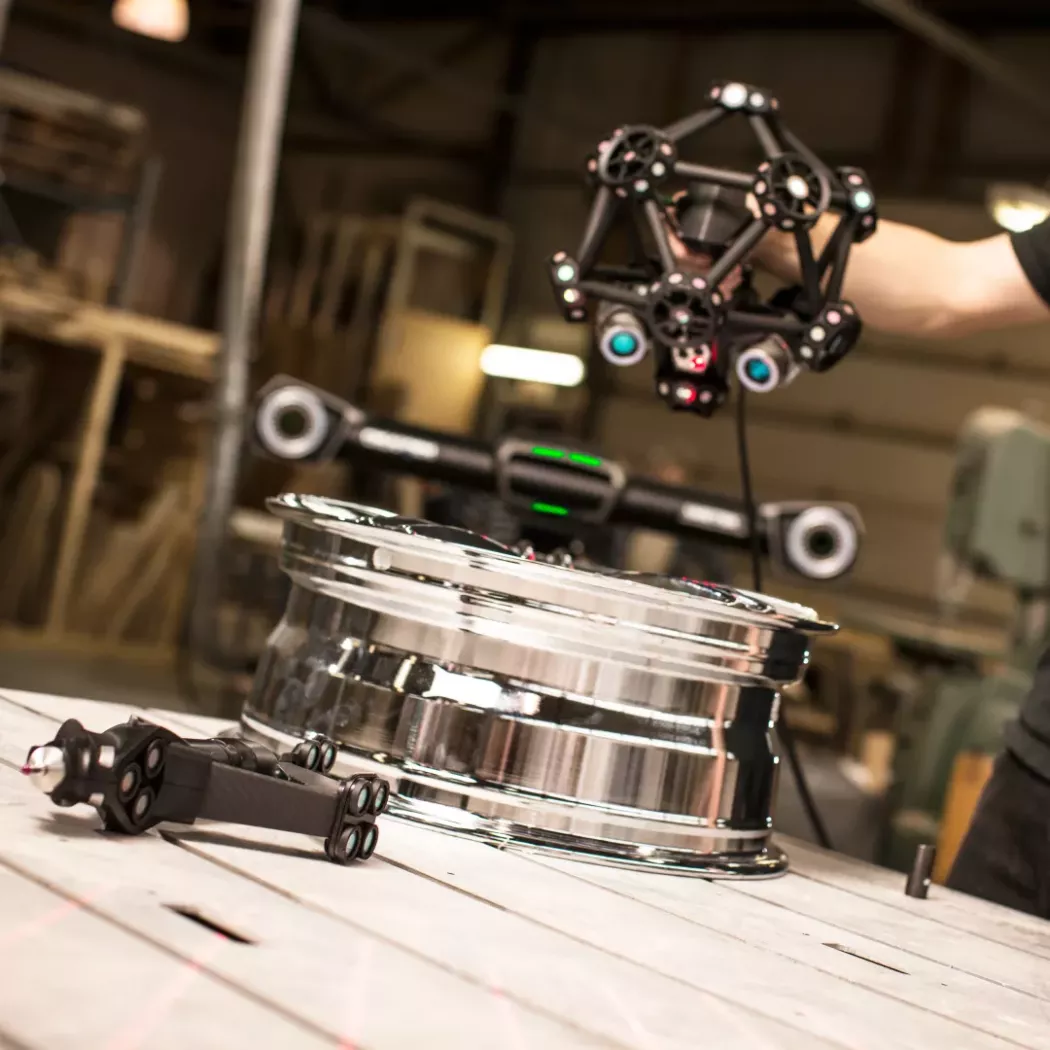 Ręczny skaner 3D MetraSCAN BLACK z&nbsp;optycznym trackerem podczas pomiaru 3D felgi aluminiowej na stanowisku kontroli jakości